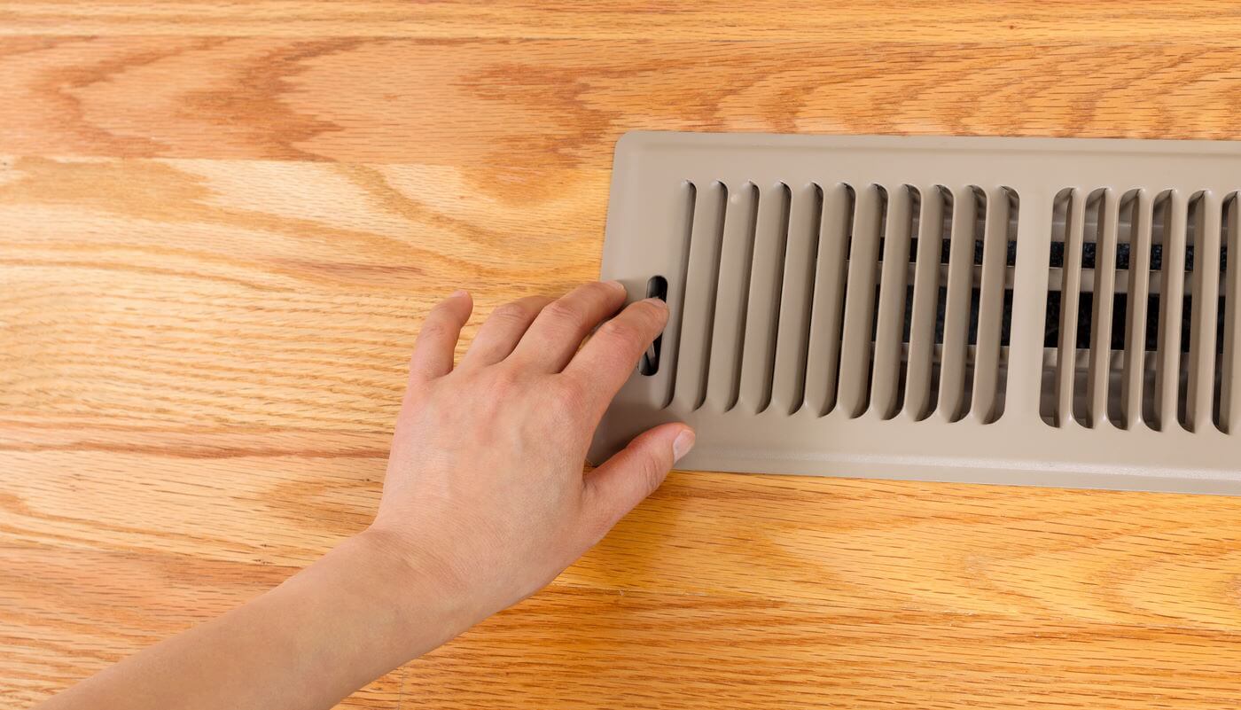 Womans hand adjusting vents on heat register 